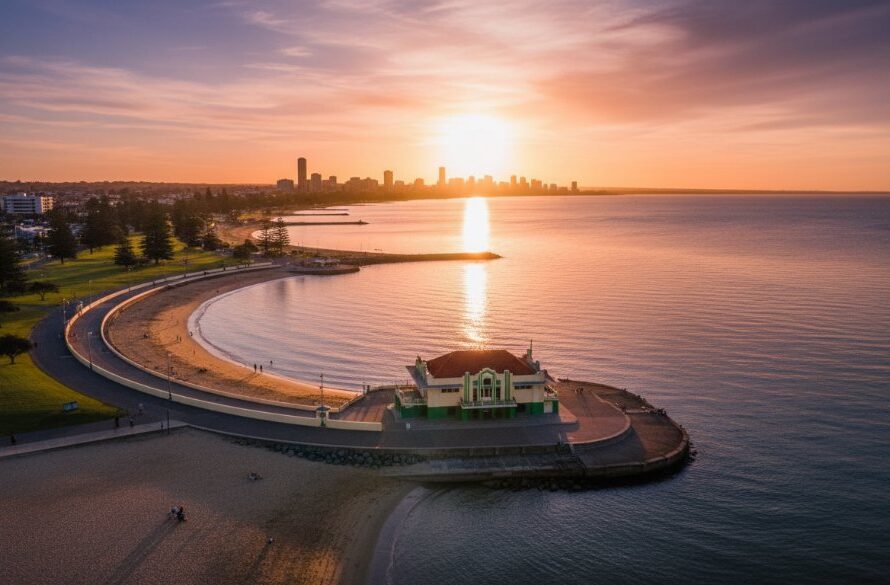 A breathtaking aerial shot of the Eastern Beach promenade and waterfront in East Geelong, captured by drone photography, showcasing golden hour light illuminating the iconic art deco bathing pavilion and vibrant foreshore activity, a truly stunning local vista.