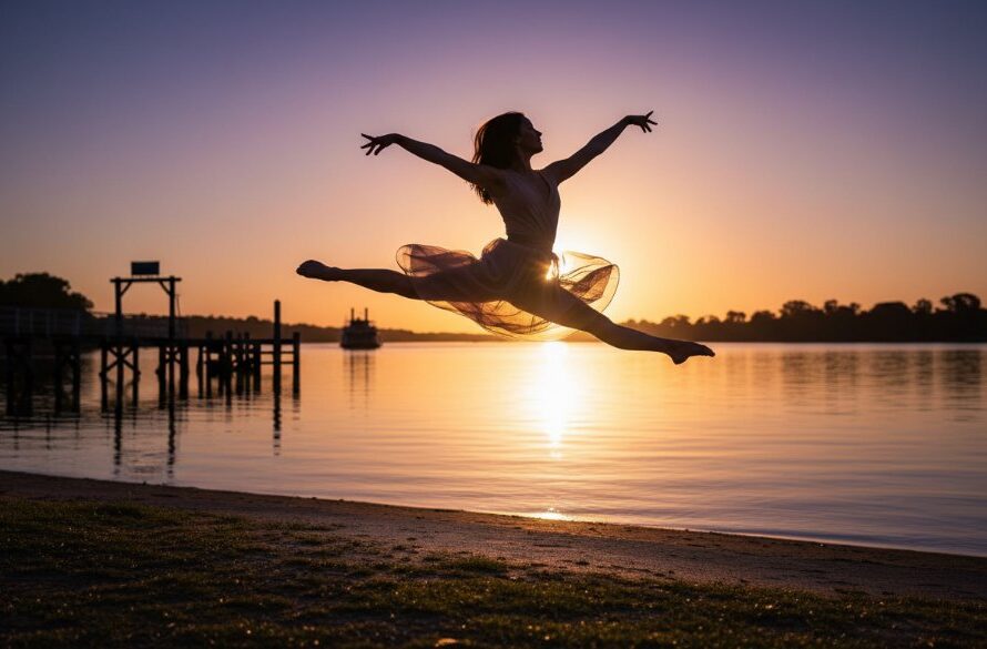 Dynamic ballet dancer in mid-leap, silhouetted against a golden Echuca river sunset, showcasing Echuca dance photography capturing river energy with dramatic lighting and a powerful pose.