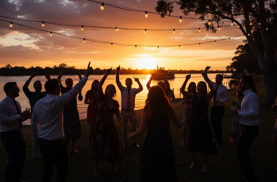 Dynamic wide-angle shot of a vibrant Echuca Waterfront Party Photography Capturing Joy, with guests silhouetted against a spectacular sunset over the Murray River, laughter frozen in time, professionally colour-graded.