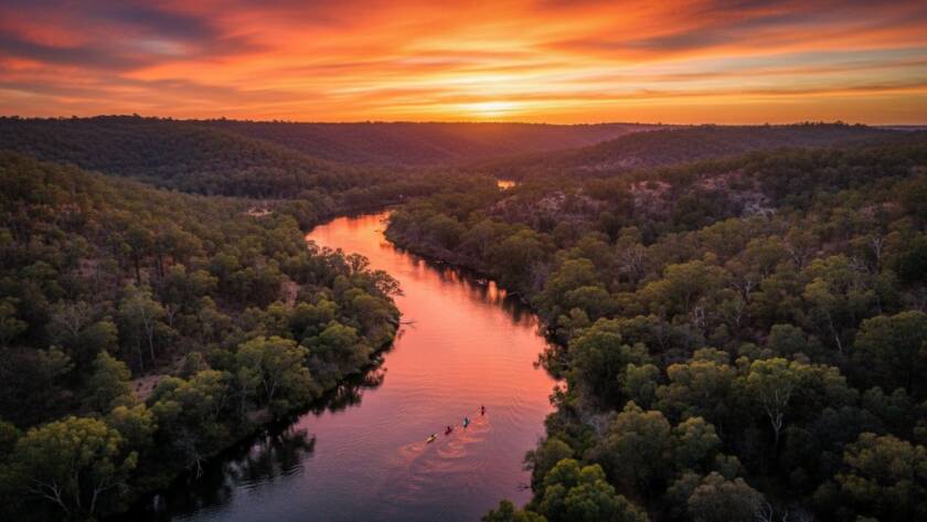 Stunning wide-angle aerial view of the Yarra River winding through Warrandyte's vibrant green bushland during a golden hour sunset, showcasing the breathtaking elevated drone photography Warrandyte Yarra River views. The light catches the water, with kayakers tiny below, creating an epic moment of natural beauty captured by drone.
