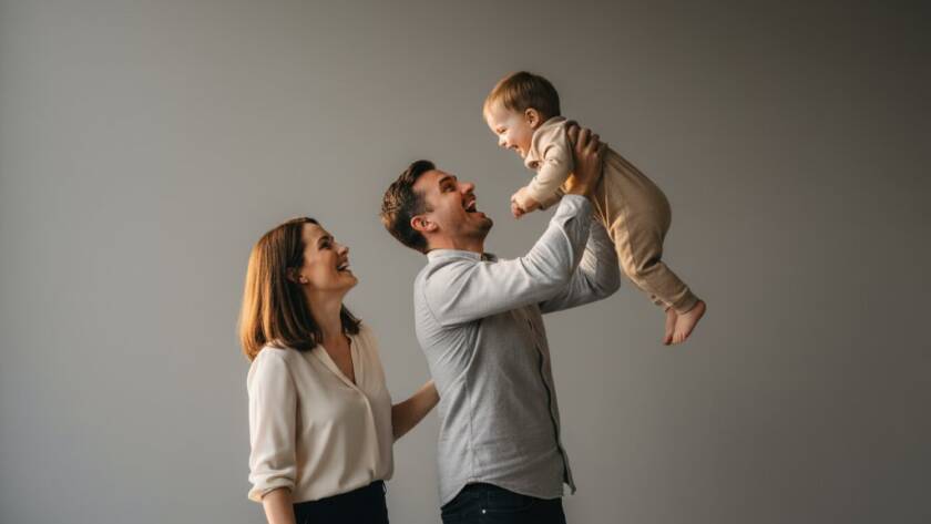 A stunning, color-graded professional photograph showcasing an 'epic moment' of a radiant family in a modern studio setting in Keilor Park, captured with elite studio photography techniques. The parents are laughing joyfully while holding their child, bathed in dramatic, soft light, creating a timeless, emotionally rich portrait.