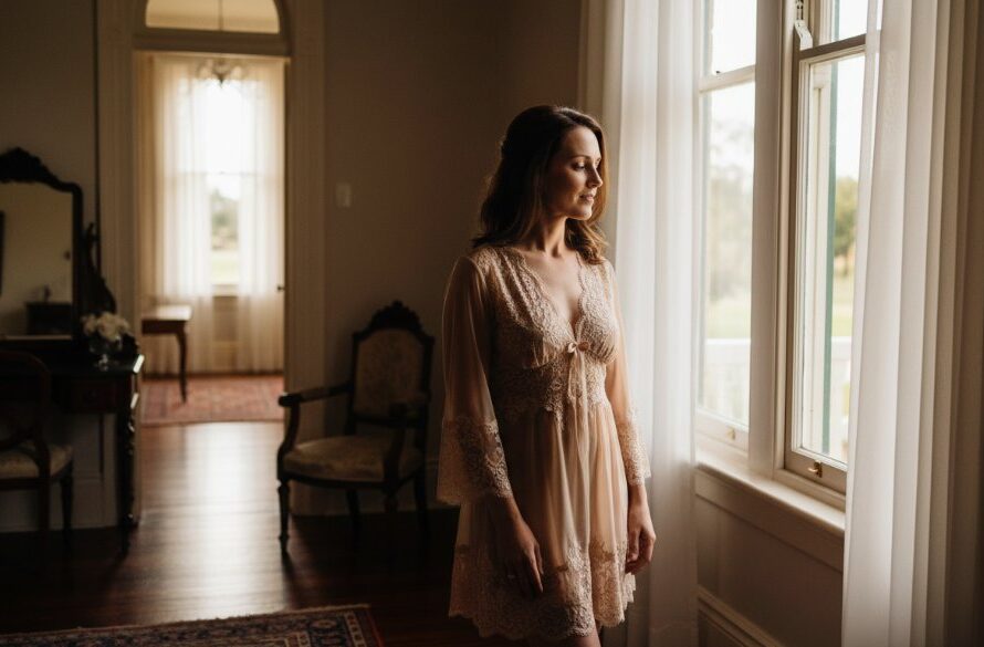 A confident woman in elegant lingerie, caught in a dramatic backlight, gazing out a window in a luxurious Maryborough heritage home, showcasing the essence of Empowering Boudoir Photography Maryborough Victoria with a powerful, intimate portrait.