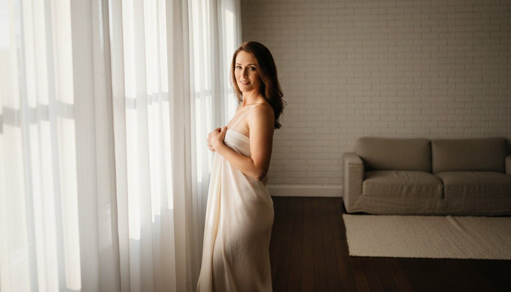 A dramatic, professionally lit photograph of a woman exuding confidence during her Empowering Boudoir Photoshoot Lang Lang Studio session, bathed in soft, ethereal light near a large window, capturing a powerful moment of self-discovery and inner strength.