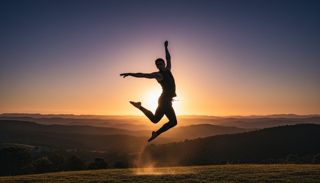 An epic moment of energetic dance photography in The Basin, showcasing a dancer mid-air, silhouetted against a golden hour sunset over the Dandenong Ranges, with dramatic backlighting highlighting powerful movement and emotion.