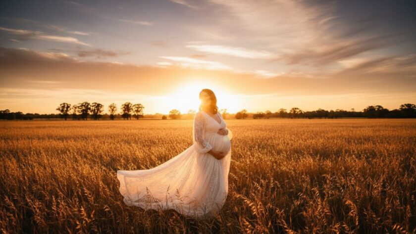 A pregnant woman in a flowing gown silhouetted against a golden sunset over Epsom Victoria, capturing an epic moment of outdoor maternity photography with dramatic backlighting.
