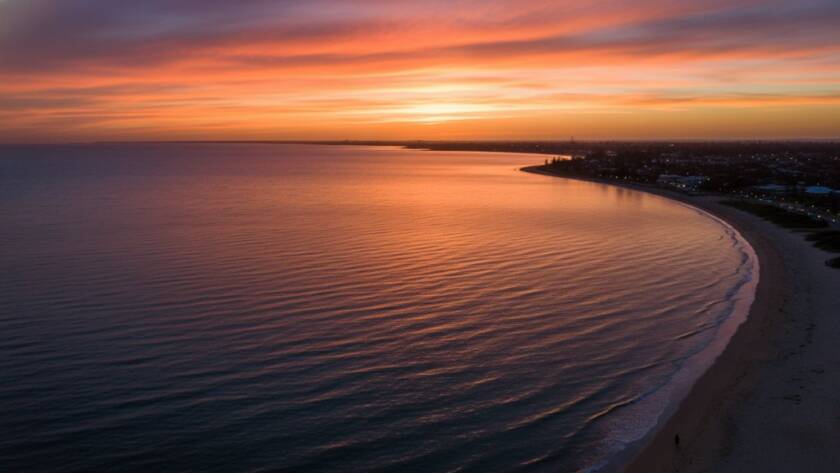An epic moment captured by expert drone photography in Chelsea Heights, showing a stunning aerial perspective of a coastal sunset over the suburb, with vibrant colours reflecting on the calm water, highlighting a picturesque landscape.