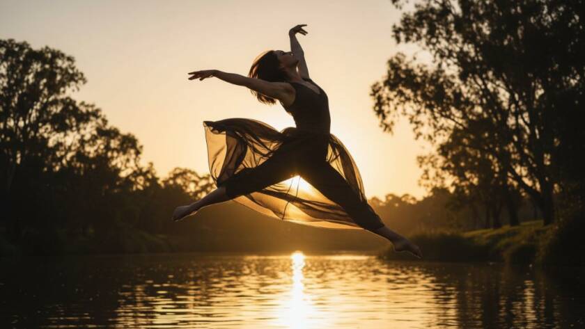 A stunning, low-angle, wide shot of a female contemporary dancer in mid-air, silhouetted against a dramatic sunset over the Yarra River in Bulleen, showcasing expressive contemporary dance photography Bulleen with dynamic motion and vibrant colour, captured at the golden hour.