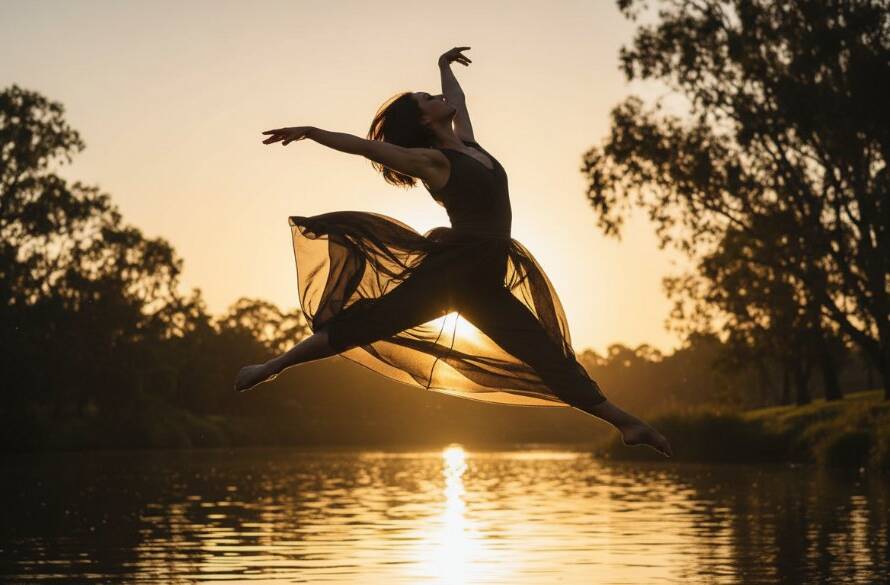 A stunning, low-angle, wide shot of a female contemporary dancer in mid-air, silhouetted against a dramatic sunset over the Yarra River in Bulleen, showcasing expressive contemporary dance photography Bulleen with dynamic motion and vibrant colour, captured at the golden hour.