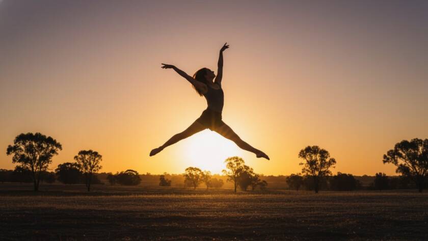 A dynamic female dancer performing a powerful leap at sunset in a rustic Kurunjang outdoor setting, captured with dramatic backlighting, embodying expressive dance photography Kurunjang Victoria.