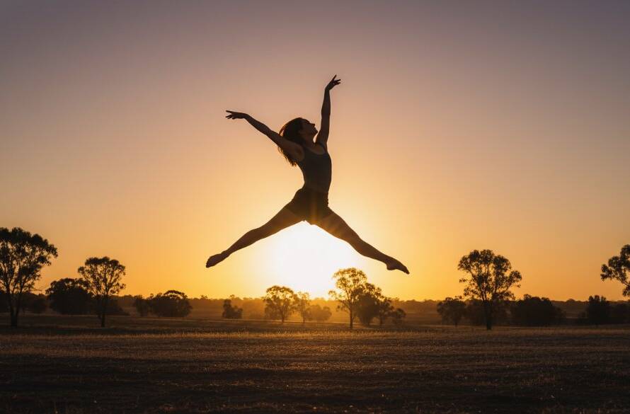 A dynamic female dancer performing a powerful leap at sunset in a rustic Kurunjang outdoor setting, captured with dramatic backlighting, embodying expressive dance photography Kurunjang Victoria.