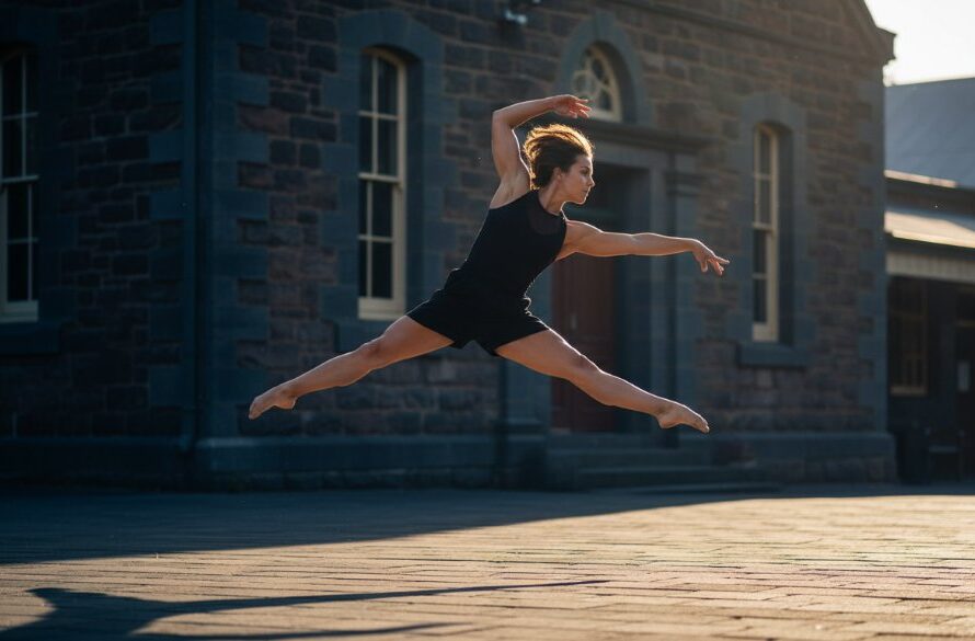 A dynamic and elegant photograph of a dancer performing an arabesque against the rustic charm of Kyneton's Bluestone Theatre, showcasing graceful Kyneton dance photography for aspiring performers with dramatic, professional lighting.