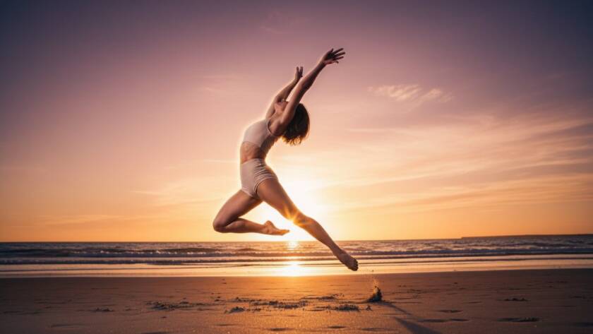 Dynamic wide shot of a ballet dancer mid-leap at sunset on the Hampton East foreshore, showcasing graceful form and the vibrant energy of Hampton East dance photography capture movement, with golden light illuminating her silhouette against a blurred coastal backdrop.