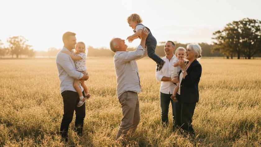 A heartwarming, sun-drenched photograph capturing genuine laughter between a family during heartfelt candid family moments in Huntly VIC, with the golden fields of regional Victoria in the background, conveying pure joy and connection. Professional color grading enhances the natural warmth.