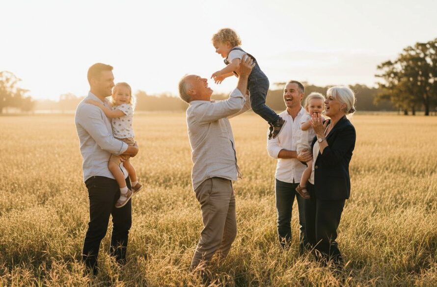 A heartwarming, sun-drenched photograph capturing genuine laughter between a family during heartfelt candid family moments in Huntly VIC, with the golden fields of regional Victoria in the background, conveying pure joy and connection. Professional color grading enhances the natural warmth.