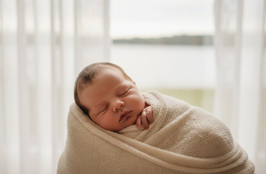 An artistic close-up photograph capturing the peaceful sleep of a newborn baby, swaddled gently, with delicate hands visible. The image embodies heartfelt newborn photography Lake Wendouree for timeless memories, featuring soft, ethereal lighting filtering through sheer curtains, evoking a sense of warmth and new beginnings.