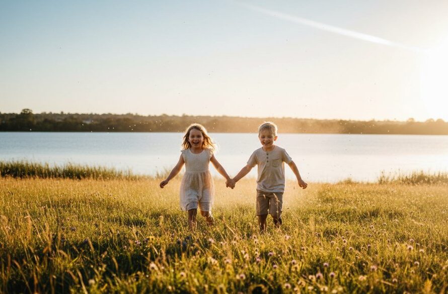 A heartwarming Ballarat Central kids photography adventures scene featuring two children laughing joyfully as they chase bubbles in the golden afternoon light at Lake Wendouree, showcasing their playful spirit with dramatic, professional lighting.