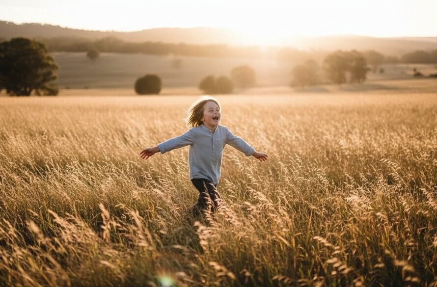 A wide-angle, cinematic photograph of a child, mid-laugh, running through a sun-drenched field in Heathcote, Victoria, with golden light flaring. This Heathcote Kids Outdoor Photography capturing genuine joy moment captures pure happiness and movement, showcasing the child's vibrant energy against the natural backdrop.