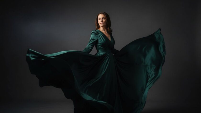 A dramatic, professionally lit Hepburn Springs studio photography for elegant portraiture of a woman in a flowing gown, captured mid-motion with soft, ethereal light highlighting her silhouette against a moody backdrop, creating an 'epic moment' of timeless beauty.