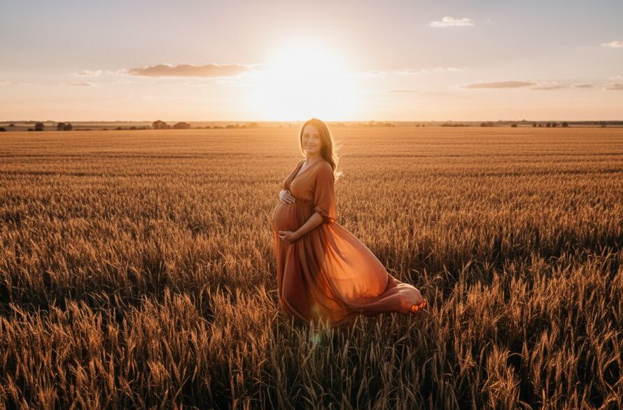 A stunning 'epic moment' photograph of a pregnant woman embracing her bump in a golden hour field in Horsham, Victoria, capturing the essence of a rustic maternity photoshoot with dramatic, warm light and professional colour grading.