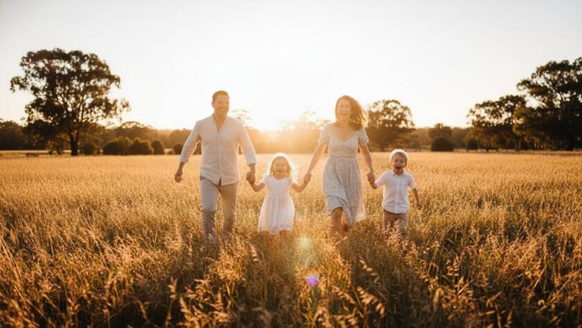 An epic moment of a family joyfully running through an open field at sunset, bathed in golden light, during their joyful family photography Croydon Victoria outdoor sessions, capturing their authentic laughter and connection.