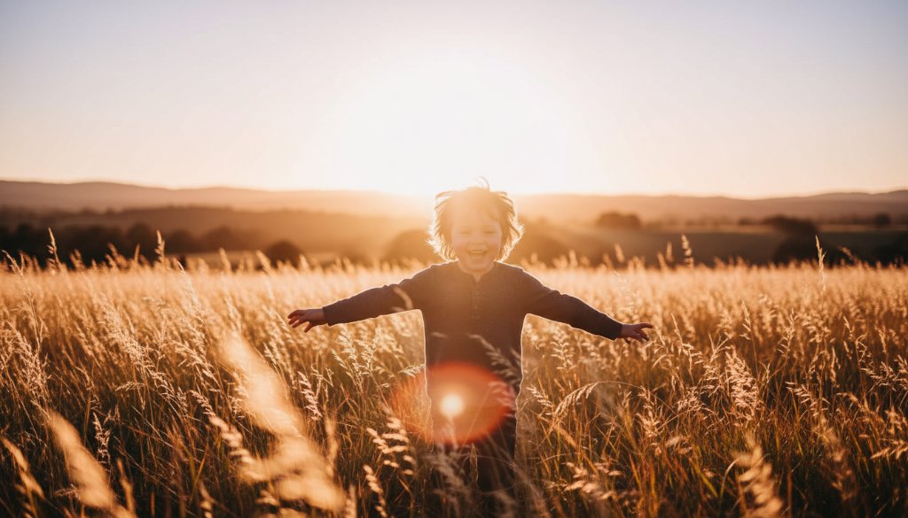 An epic, sun-drenched photograph capturing a child's joyful, uninhibited laughter while running through golden fields near Hamilton, Victoria, embodying the spirit of Joyful Kids Photography Hamilton Victoria.