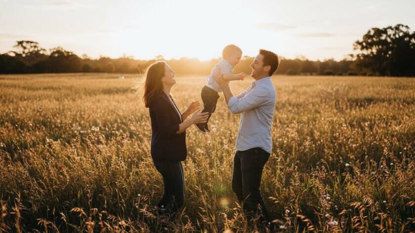A Kealba family photographer candid moments Victoria capture of parents laughing while gently tossing their toddler in the air against a warm, golden hour backdrop in a Kealba park, evoking pure joy and connection.