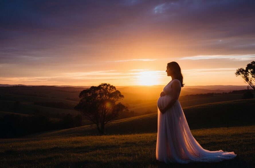 An expectant mother in a flowing gown stands silhouetted against a dramatic Kilmore sunset, capturing Kilmore enchanting outdoor maternity photography with golden hour light and the rolling Victorian hills in the background, exuding serene beauty and anticipation.