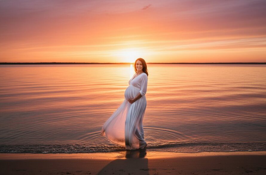 A glowing mother-to-be in a flowing gown stands silhouetted against a dramatic sunset at Lakes Entrance, capturing an epic Lakes Entrance maternity photography iconic sunset session with vibrant orange and purple hues reflecting on the water, embodying serene anticipation.