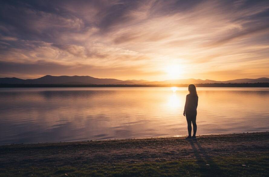 A breathtaking Lysterfield fine art photography dramatic light portraits scene, featuring a lone figure silhouetted against a golden hour sky reflecting off Lysterfield Lake, with dramatic rays of light piercing through clouds, evoking deep emotion.