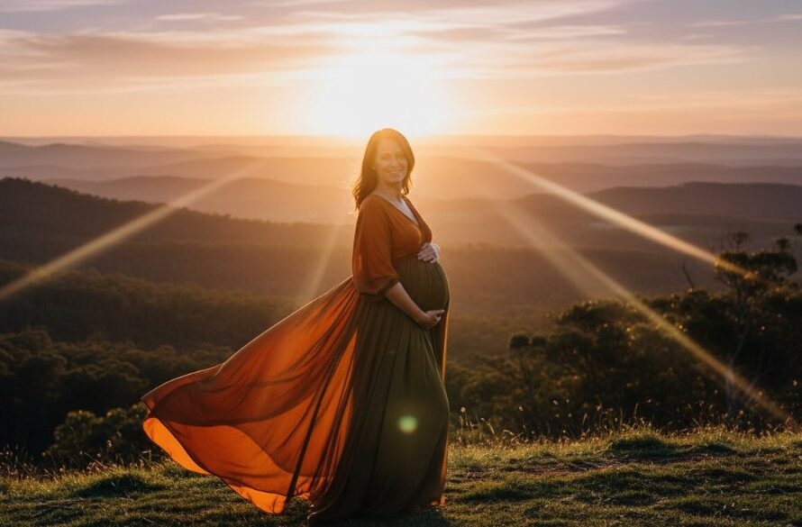A glowing expectant mother, silhouetted against a dramatic sunset over the rolling hills of the Macedon Ranges, lovingly cradles her baby bump in a stunning scene capturing Macedon Ranges bespoke maternity portraits with cinematic light.