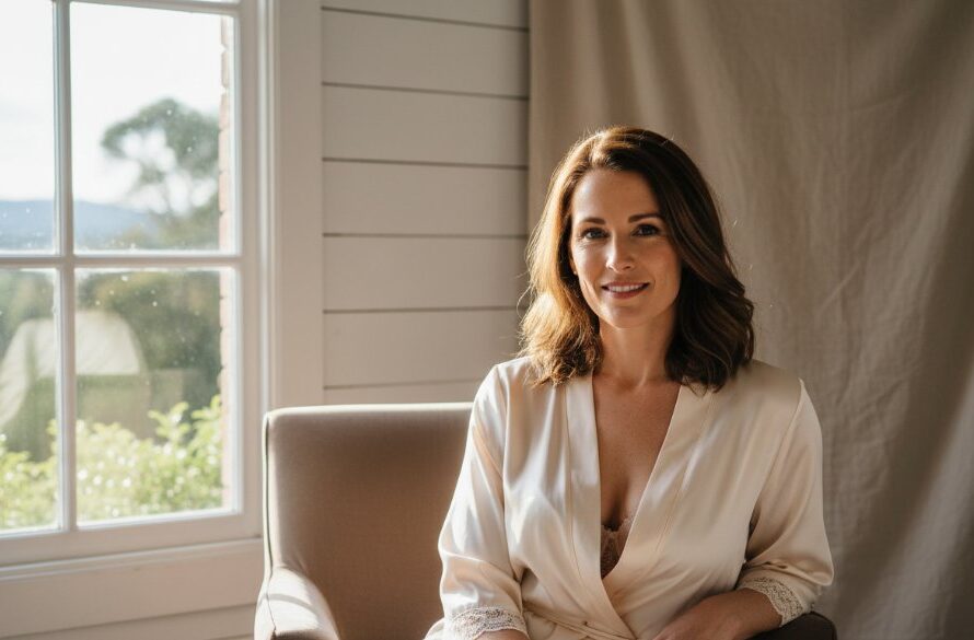 A beautifully composed, naturally lit portrait capturing an empowering moment of a woman during her Macedon Ranges intimate boudoir photography session, set against a luxurious, subtly rustic backdrop in a Macedon studio, showcasing her confidence and natural beauty with professional colour grading.