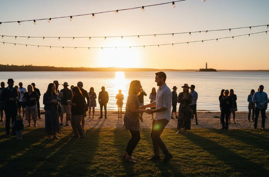 A wide shot capturing the vibrant energy of a community festival along the Mallacoota lake foreshore, featuring attendees laughing and dancing under string lights at dusk, showcasing expert Mallacoota lakeside event photography capturing genuine joy.