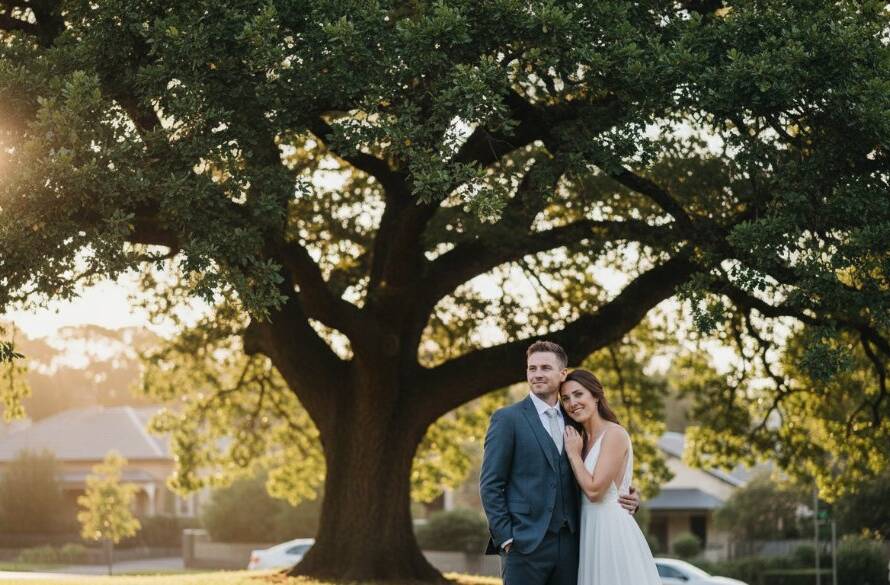 A beautifully composed, candid photograph capturing a joyful newlywed couple sharing an intimate laugh during their Malvern East Wedding Photography Candid Moments, with soft, golden hour light filtering through mature oak trees in a Malvern East garden, showcasing genuine emotion and the picturesque local setting.