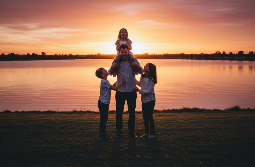 An epic moment of a family laughing joyfully by the lake at sunset in Manor Lakes, showcasing professional Manor Lakes family photography capturing genuine joy, with warm golden hour light and a cinematic, colour-graded finish.