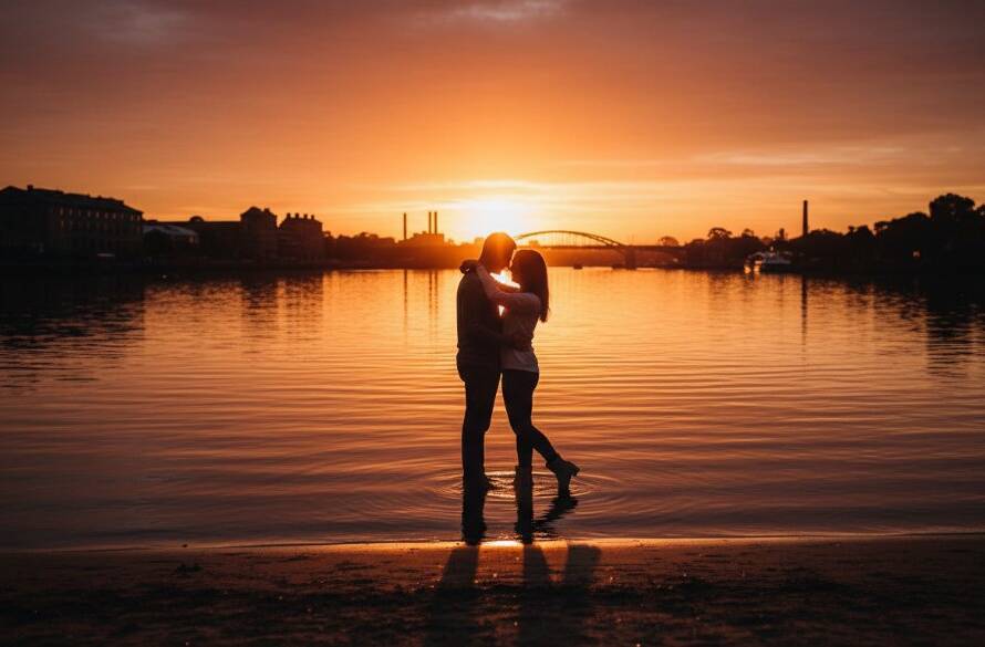 An ethereal Maribyrnong fine art photography historic riverside moment featuring a silhouetted couple embracing at sunset by the Maribyrnong River, golden light reflecting on the water, capturing a timeless, intimate connection.