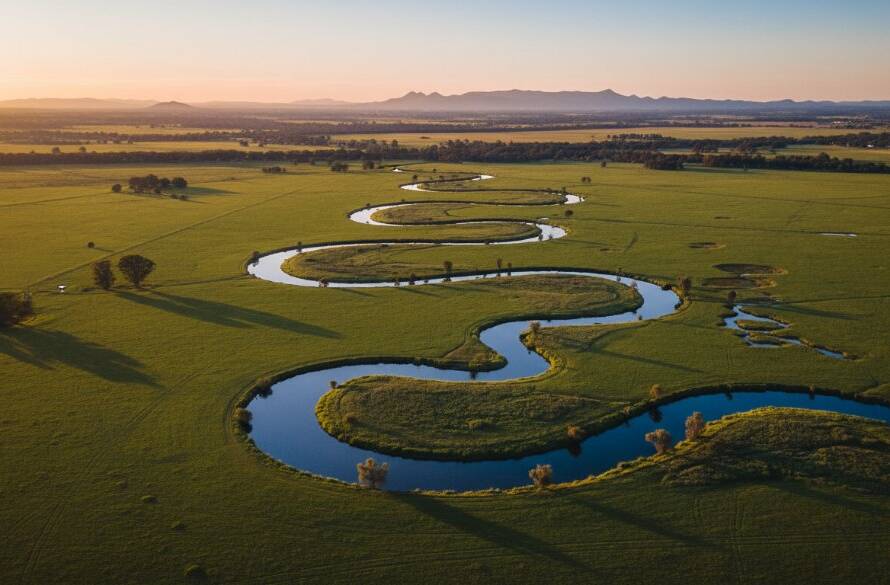A professional drone photograph capturing the dramatic golden hour over Melton South, featuring the Werribee River winding through lush green fields, with the distant You Yangs framed majestically under a vibrant sky, showcasing Melton South drone photography epic aerial views.