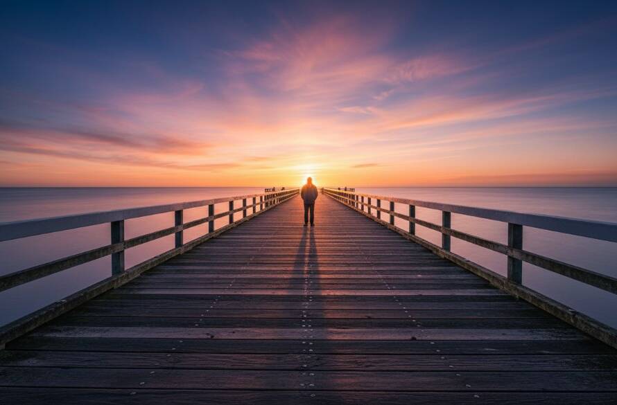 A dramatic wide shot of a solitary figure silhouetted against a vibrant sunset at Mentone Beach, expertly showcasing Mentone beach fine art photography captures the raw beauty of the coastline with stunning light and atmosphere.