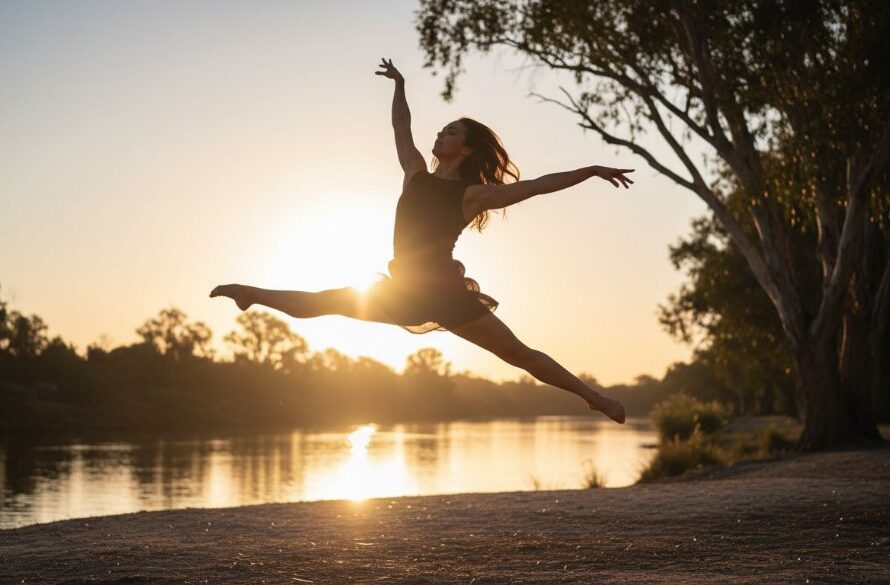 Dynamic wide shot capturing Mildura contemporary dance photography vibrant energy, featuring a dancer in an elegant, powerful jump against a dramatic sunset backdrop over the Murray River, showcasing incredible athletic form and artistic expression. The scene is professionally lit and colour graded.