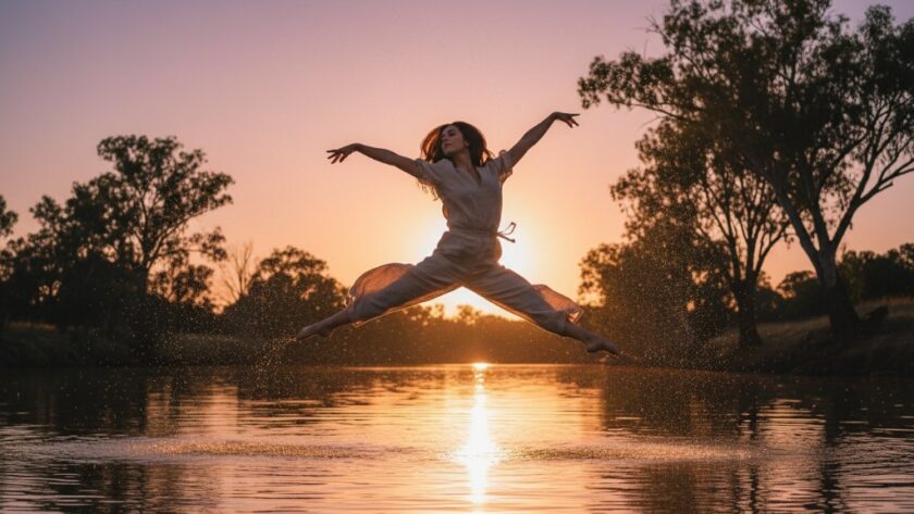 A powerful Moama contemporary dance photography Murray River shot featuring a dancer mid-leap at sunset, with the golden glow reflecting off the river, capturing an epic moment of strength and artistry.