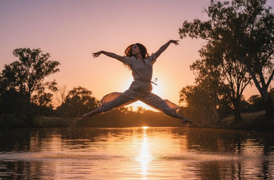 A powerful Moama contemporary dance photography Murray River shot featuring a dancer mid-leap at sunset, with the golden glow reflecting off the river, capturing an epic moment of strength and artistry.