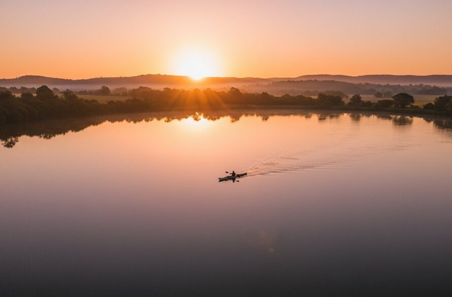 An epic moment captured by Moe Victoria drone photography elevated perspectives, showing the sunrise over Lake Narracan with a lone kayaker, dramatic light, and lush green surrounds.