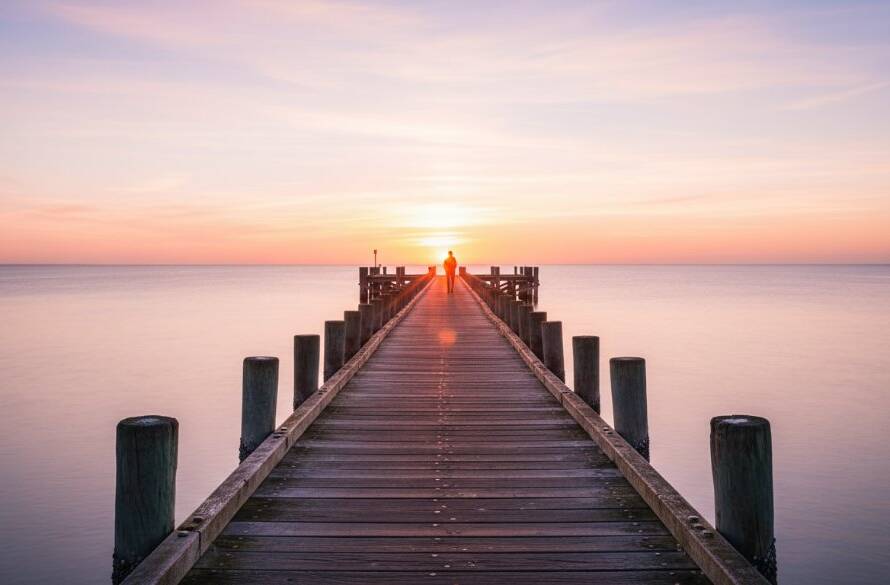 An epic moment in Mordialloc Fine Art Photography: Coastal Soul Captured Beautifully, featuring a lone figure silhouetted against a dramatic, fiery sunset over the Mordialloc pier, waves crashing gently, with professional colour grading creating a serene and powerful artistic scene.