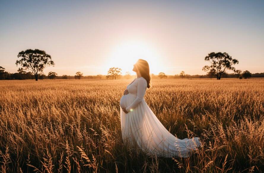 A radiant expectant mother in Mulgrave, Victoria, during an outdoor maternity photoshoot, her silhouette dramatically lit by golden hour sun filtering through eucalyptus trees, embodying an epic moment of serene anticipation.