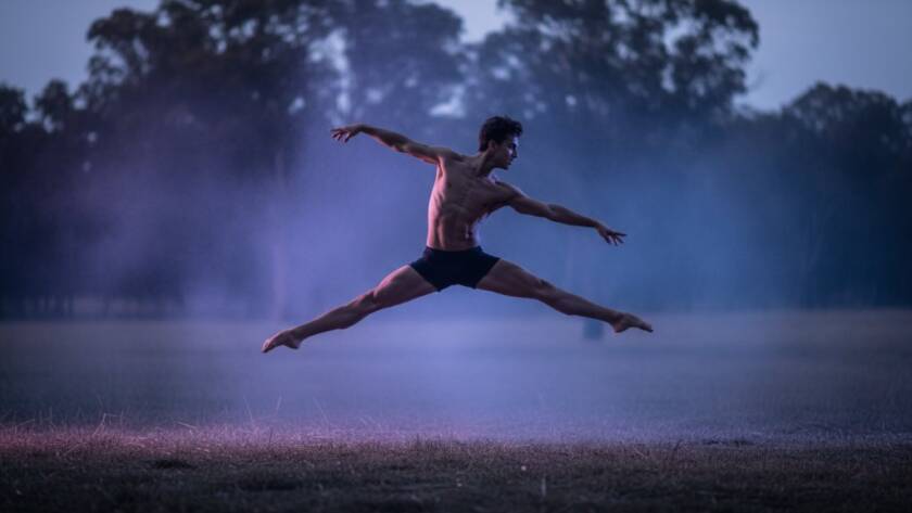 A male dancer captured mid-air in an awe-inspiring leap during a Narre Warren North dynamic dance photography session, with dramatic backlighting silhouetting his form against a misty, ethereal backdrop, conveying raw power and grace.