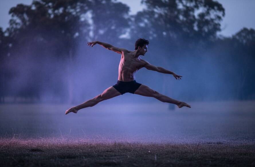 A male dancer captured mid-air in an awe-inspiring leap during a Narre Warren North dynamic dance photography session, with dramatic backlighting silhouetting his form against a misty, ethereal backdrop, conveying raw power and grace.