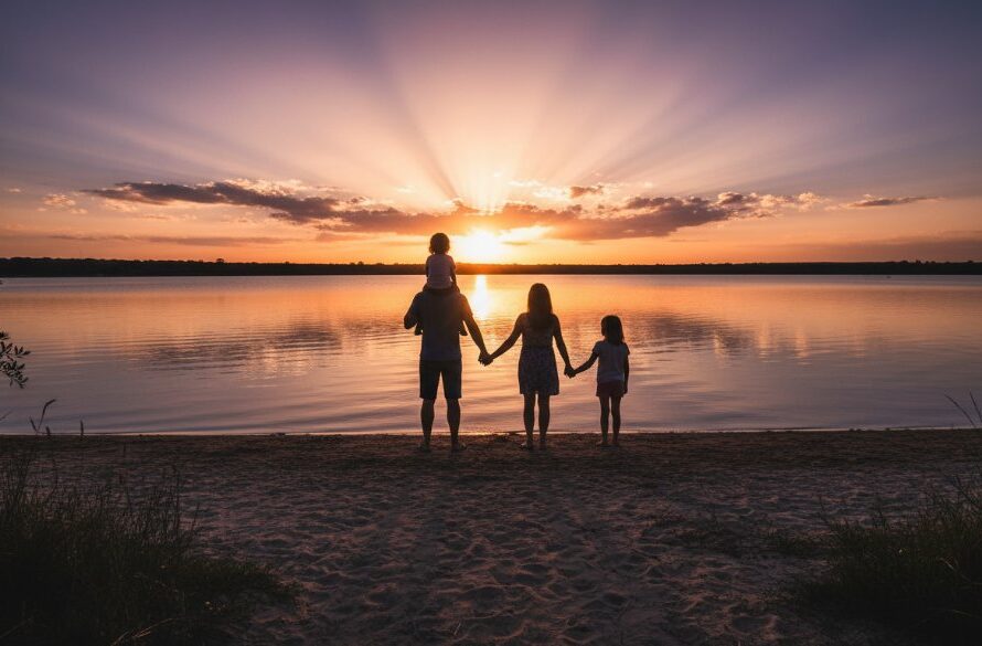 An emotive wide-angle shot by a Newborough family photographer capturing genuine moments, featuring a family silhouetted against a golden hour sunset over the tranquil Lake Narracan, parents embracing children as they laugh, with warm, cinematic lighting and professional colour grading.
