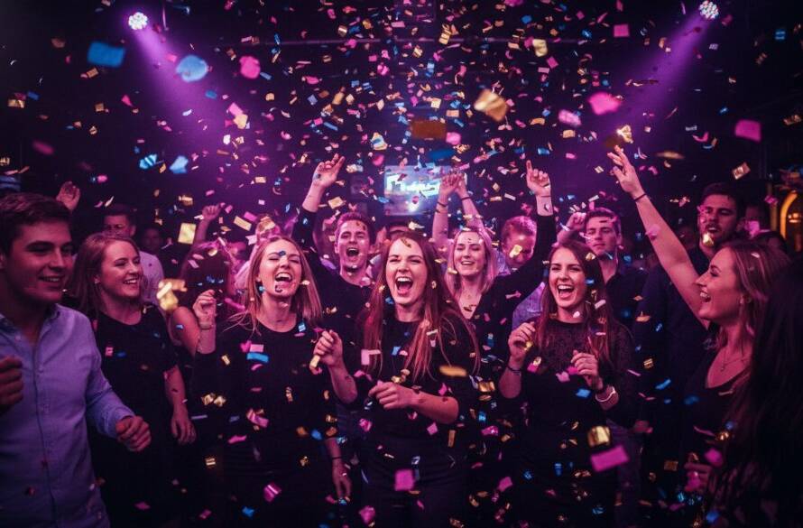 An energetic, wide-angle, low-light shot captured by a Notting Hill Victoria party photographer capturing joy, showing guests dancing ecstatically under vibrant club lights, confetti mid-air, hands raised in celebration, perfect for an 'epic moment' style photograph.