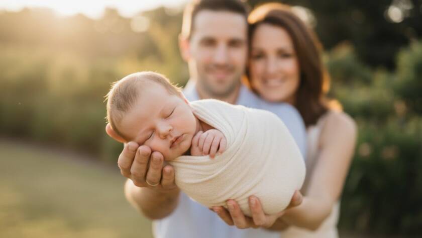 An intimate and beautifully lit Oakleigh newborn photography precious moments capture, featuring a peaceful baby swaddled in soft fabrics, held gently by parents, with a shallow depth of field highlighting their tiny features and the emotional connection.