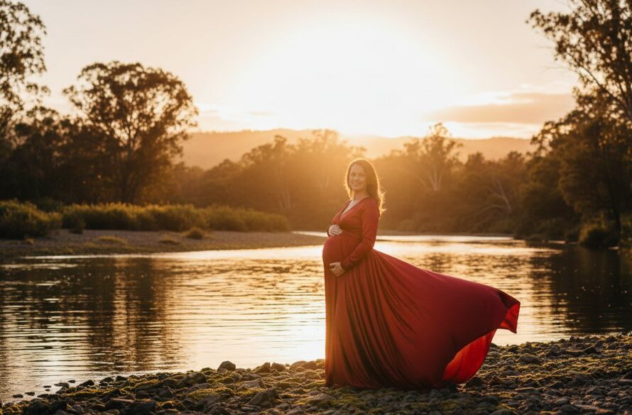 A stunning Orbost riverside maternity photoshoot Victoria featuring a radiant mother-to-be, silhouetted against a golden hour sky by the Snowy River, her flowing dress catching the soft breeze, evoking an epic moment of serene anticipation.
