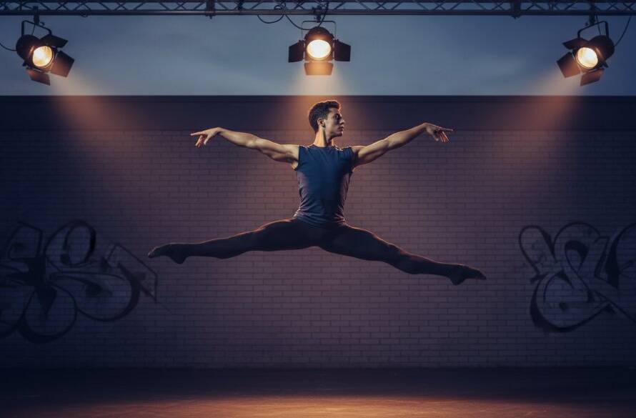 An electrifying 'epic moment' photograph capturing a dancer mid-air, bathed in dramatic stage lighting, showcasing passionate Mulgrave dance photography vibrant artist portraits. The dancer's powerful leap is frozen in time against a blurred urban Mulgrave backdrop at dusk, emphasizing raw emotion and athletic grace.